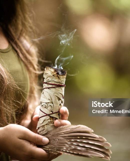 Young caucasian woman burning sage, practicing a purification ritual